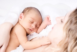 Baby schläft an der Brust seiner Mutter