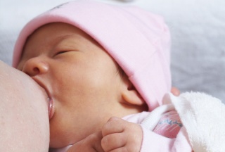 Baby mit Mützchen beim Stillen